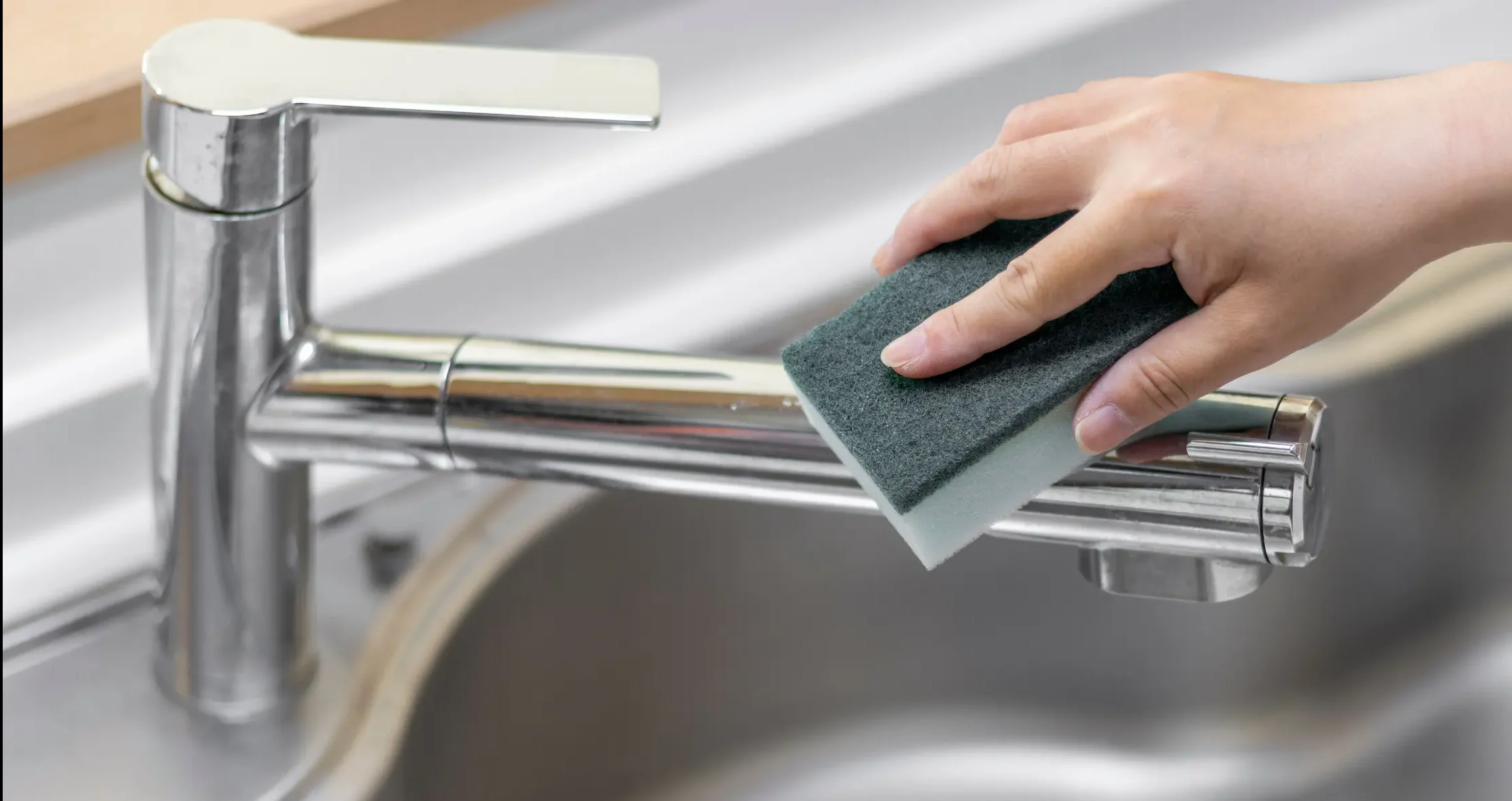 スポンジでステンレスシンクの水垢を掃除する様子